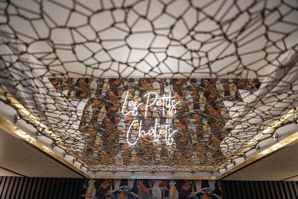 A ceiling with a net-like structure and a neon sign reading "Les Petits Châteaux". - Les Petits Chalets (Val-des-Lacs)