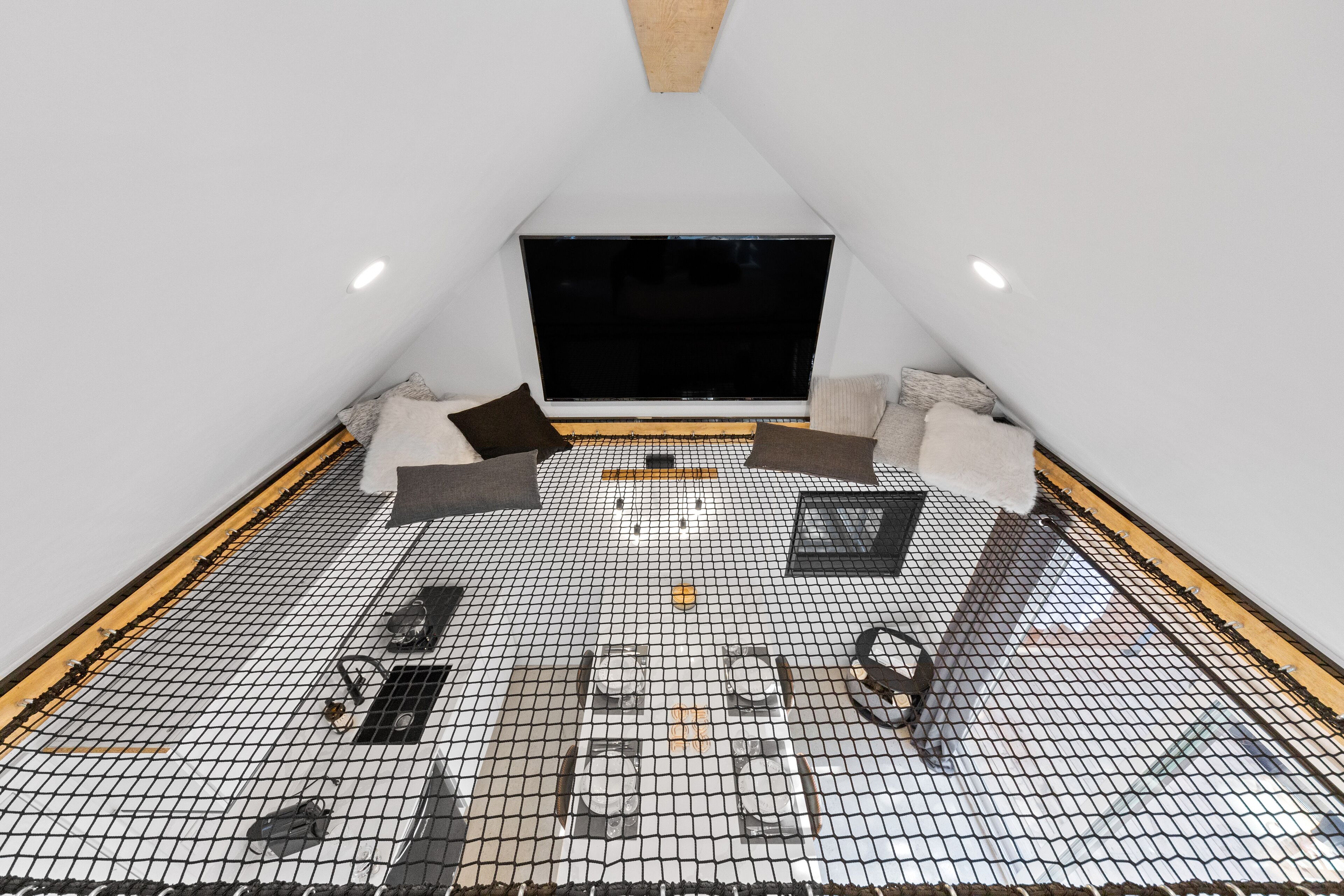 A small, triangular room with a black screen at the front, a white ceiling, and a floor covered with a black and white grid pattern.