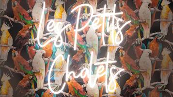 A neon sign with parrots and the text "Leg Petts Chalet".