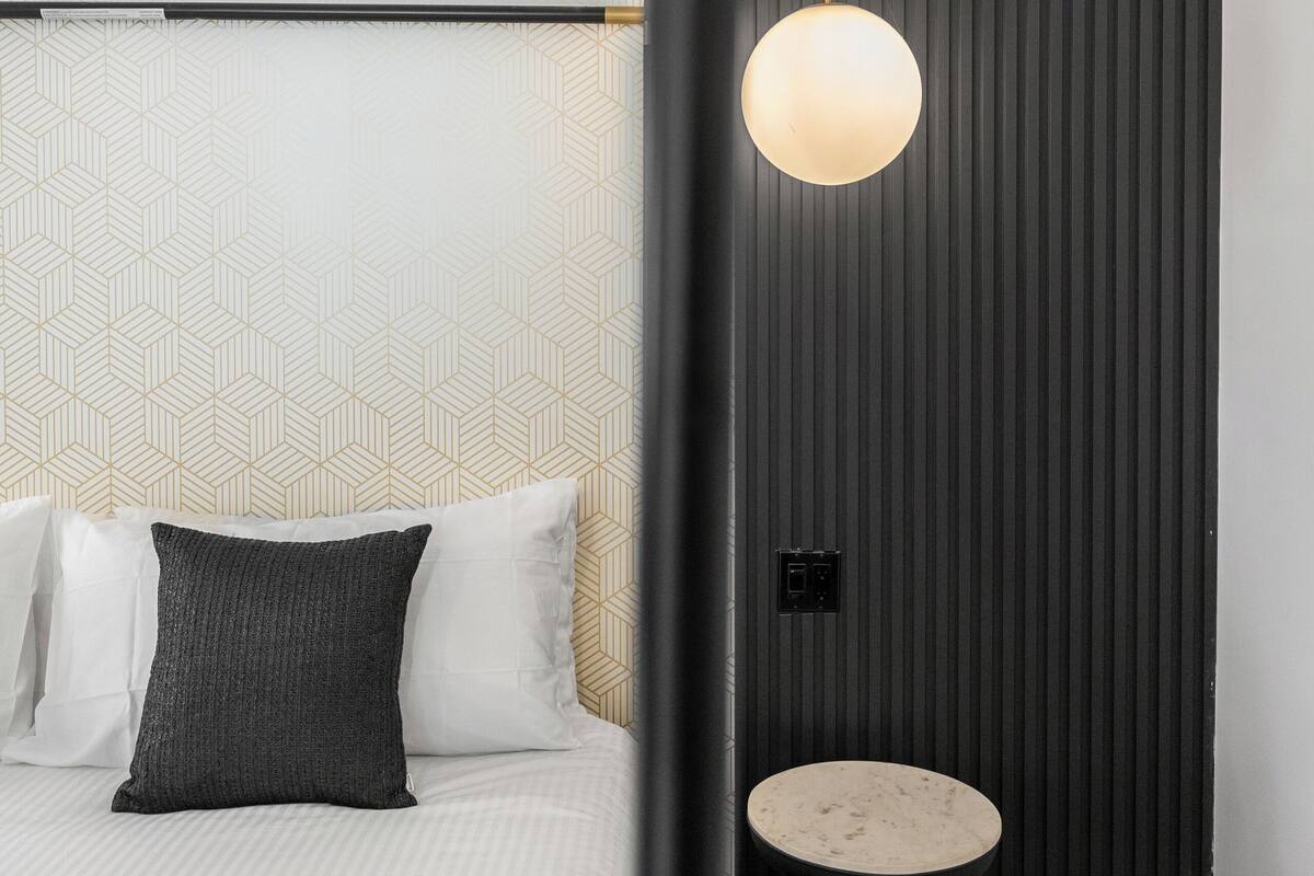 Une chambre d’hôtel moderne, équipée d’un lit, d’une table ronde et d’un luminaire fixé au mur.