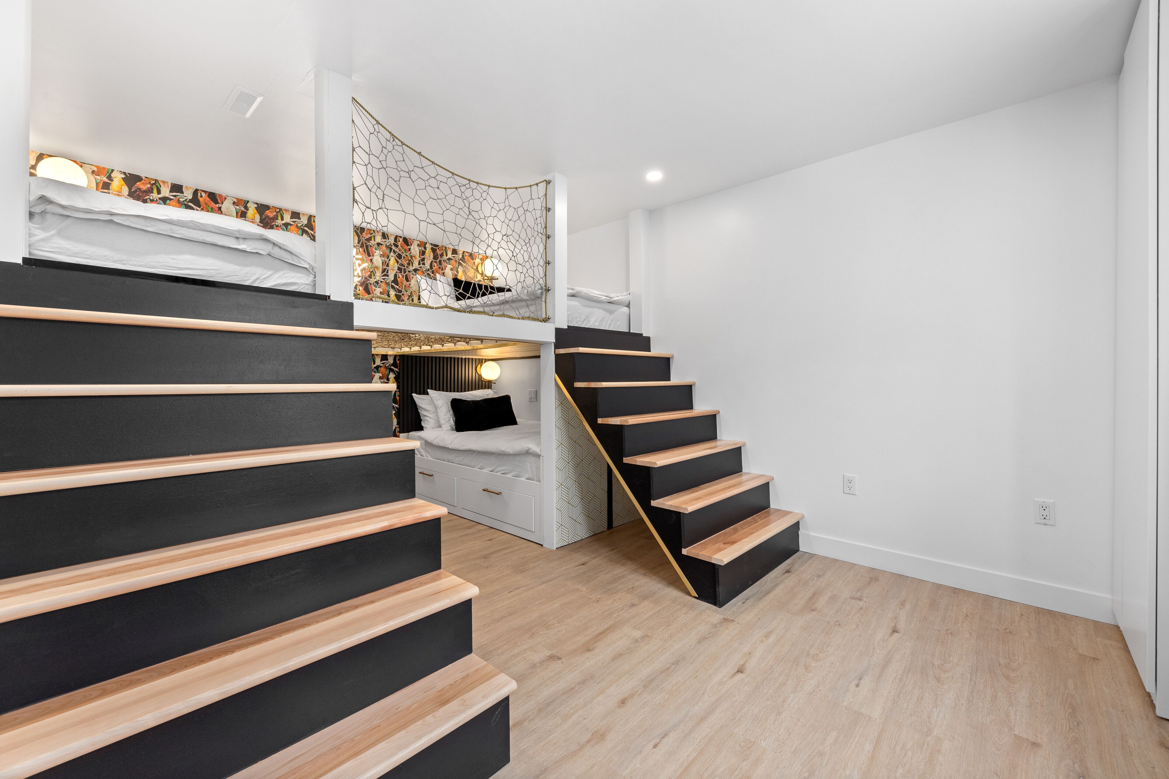 A modern interior with a staircase leading to a loft bedroom, featuring a unique ceiling design and a cozy seating area.