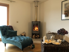 A cozy living room with a blue sofa, a fireplace, wicker baskets, and a vase with flowers.