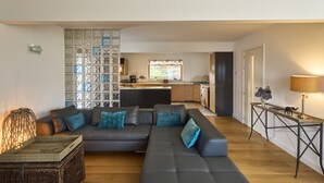 A modern living room with a grey sectional sofa, a wicker side table, and a wooden floor.