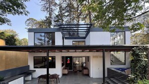 A modern two-story house with a covered patio, a staircase, and a garden area. - House with hottub (Valle de Bravo)