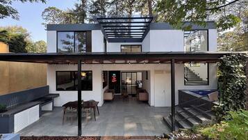 A modern two-story house with a covered patio, a staircase, and a garden area.