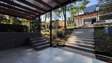 A modern outdoor area with a covered patio, stone steps, and a view of a building.