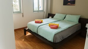 A bedroom with a bed, two windows, a painting on the wall, and wooden flooring. - House with pool near Verbania and Lake Maggiore (Cissano)