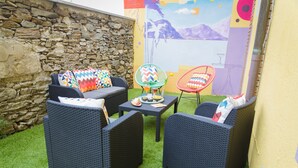 An outdoor seating area with wicker furniture and a stone wall. - House with pool near Verbania and Lake Maggiore (Cissano)