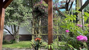 En pergola af træ omgivet af frodigt grønt og blomstrende planter.