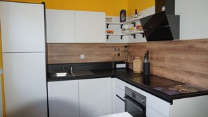 A modern kitchen with white cabinets, a black countertop, and wooden backsplash. - Spacious holiday apartment with terrace and garden (Bindlach)