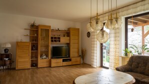 A living room with wooden furniture, a TV, and a sofa. - Spacious holiday apartment with terrace and garden (Bindlach)