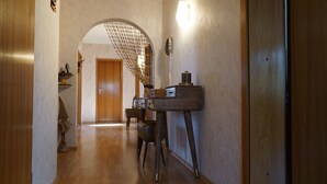 A hallway with a wooden door, a small table with drawers, and a decorative item on the wall. - Spacious holiday apartment with terrace and garden (Bindlach)