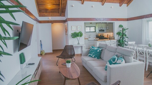 A modern living room with a sofa, a coffee table, and a TV mounted on the wall. - Cozy Entire Villa with Picuzzi (La Romana)