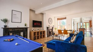 A modern living room with a pool table, a blue sofa, and a fireplace. - Thrift House • Central Location • Pool Table • Free Parking • Smart TV • Fast WiFi • Yoko Property (Northampton)