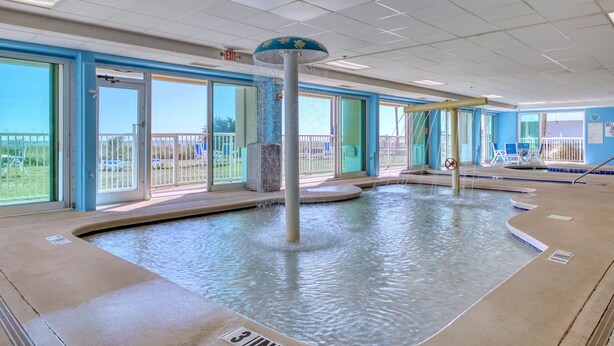 A pool area with a water feature, glass doors, and a view of the outdoors.