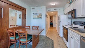 A kitchen with a dining table, chairs, a refrigerator, stove, microwave, and cabinets.