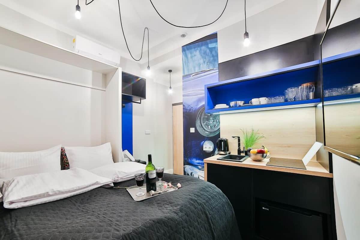 Una habitación de hotel moderna con una cama grande, un escritorio con computadora y un televisor montado en la pared.