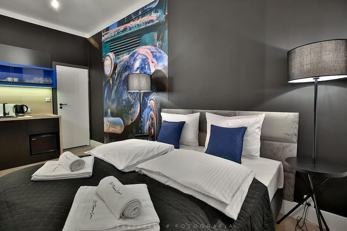 Habitación de hotel con una cama grande, un escritorio con hervidor y un mural en la pared.