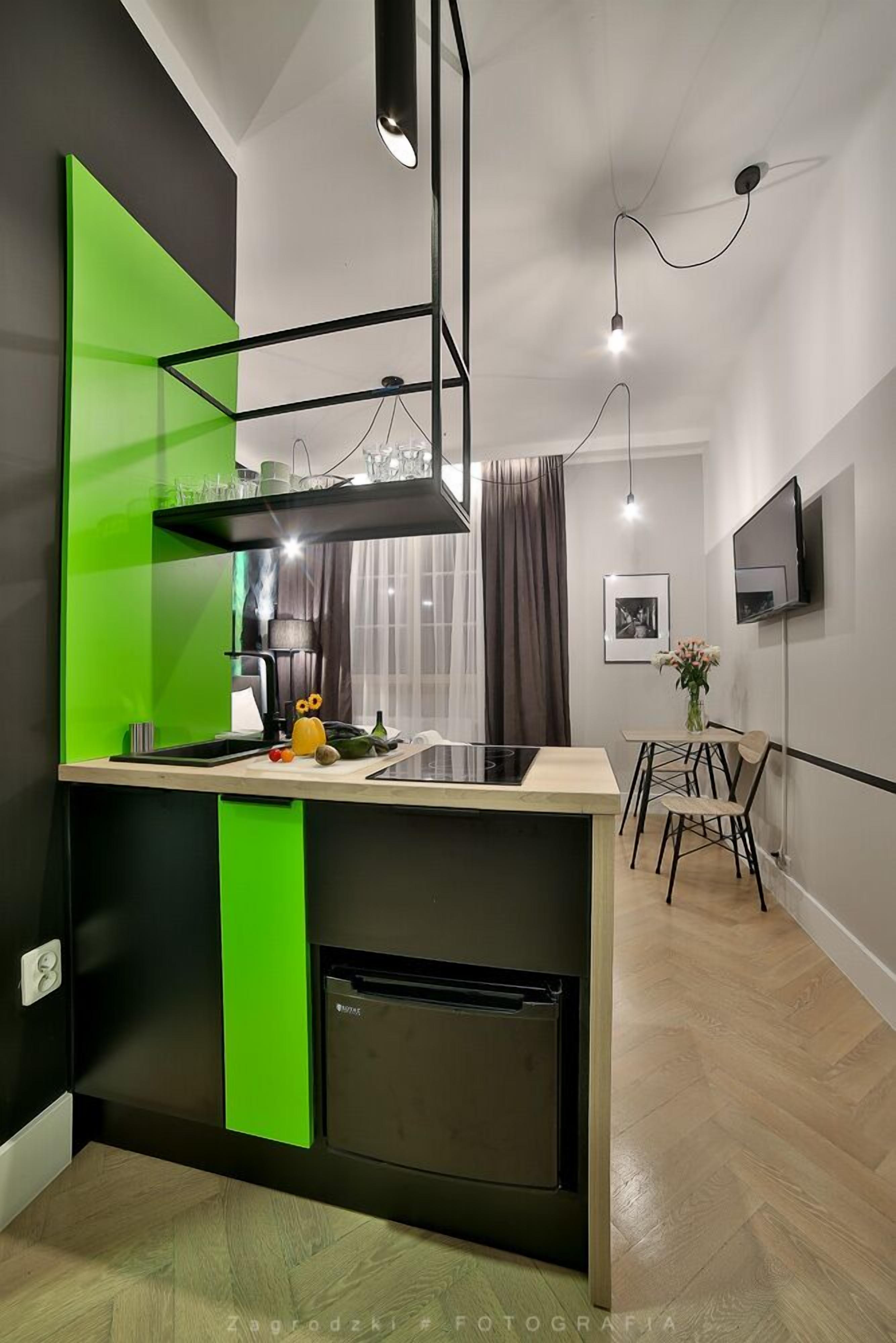 A modern kitchen with a green accent wall, a built-in oven, and a dining area with a table and chairs.