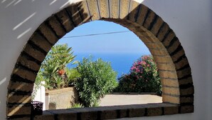 Une vue à travers une fenêtre en arc de cercle, avec un ciel bleu dégagé et une végétation luxuriante.