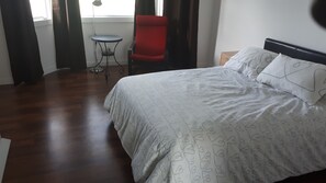Una camera da letto con un letto, una sedia rossa, un tavolino e una finestra con tende.