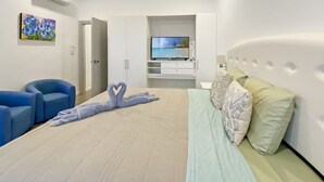 A modern hotel room with a large bed, a TV, a desk, and a chair. - Ocean view Condo - Best beach location (Jaco)