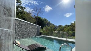 A clear pool with a stone wall and a lounge chair. - Ocean view Condo - Best beach location (Jaco)