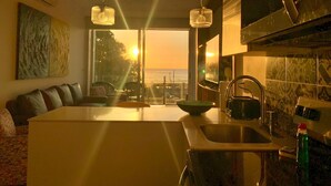 A modern kitchen with a large island, a dining area with a view of the ocean, and a large artwork on the wall. - Ocean view Condo - Best beach location (Jaco)