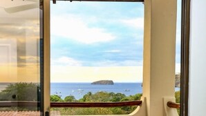 Una stanza con un letto, una finestra vista mare e un balcone.
