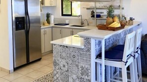 Una cucina moderna con frigorifero in acciaio inossidabile, forno integrato e un'ampia isola con sgabelli da bar.