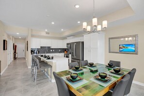 A modern kitchen with white cabinets, a central island, and a dining area with a table set for four.