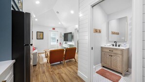 A modern kitchen with a black refrigerator, wooden cabinets, and a white countertop.