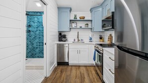 A compact kitchen with white cabinets, a stainless steel refrigerator, and a dishwasher.