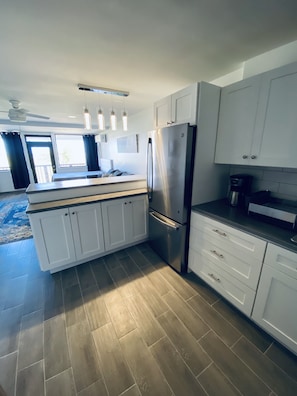 A modern kitchen with white cabinets, a stainless steel refrigerator, and a central island.