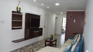 A living room with a sofa, TV, and shelves.
