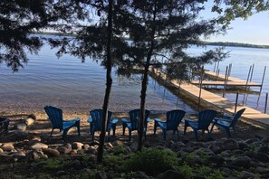 Relax by the serene lake with a dock extending into the water, surrounded by trees and rocks.