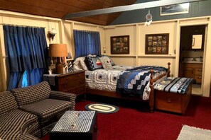 Relax in this inviting bedroom with a large bed, nightstands, and a dresser, complemented by a cozy seating area and framed artwork.