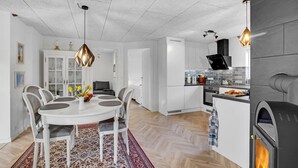 A modern kitchen with white cabinetry, a built-in oven, and a wood-burning stove. - Stunning home in Sjællands Odde (Sjællands Odde)