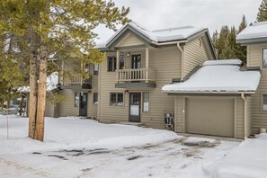 A two-story building with a balcony on the second floor, a garage, and a snow-covered ground.