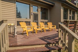 Une terrasse en bois avec quatre chaises Adirondack jaunes et une petite table.