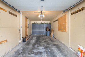 Un garage avec un sol en béton, un ventilateur de plafond et une porte dotée d’une fenêtre.