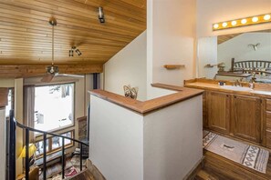 Une salle de bain moderne avec des éléments en bois, un meuble-lavabo avec un miroir et un ventilateur de plafond.