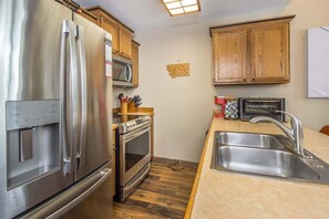 Une cuisine équipée d’appareils électroménagers en acier inoxydable, de meubles de rangement en bois, d’un four à micro-ondes, d’un grille-pain et d’un évier.