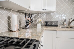 A kitchen with white cabinets, a granite countertop, a gas stove, a paper towel holder, a knife block, a basket, and a soap dispenser. - Best views of south side St. Thomas (St. Thomas)