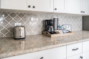 A kitchen with a toaster, coffee maker, and a tray with food items.