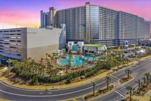 A large hotel with multiple floors, a central pool area, and a parking garage.