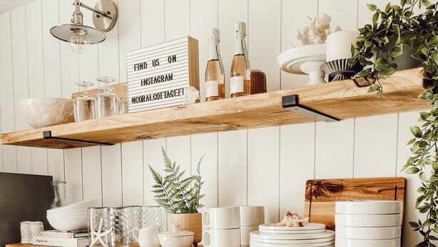 Una cocina con estantes de madera que sostienen vajilla y un cartel que dice 'Encuéntranos en Instagram'.