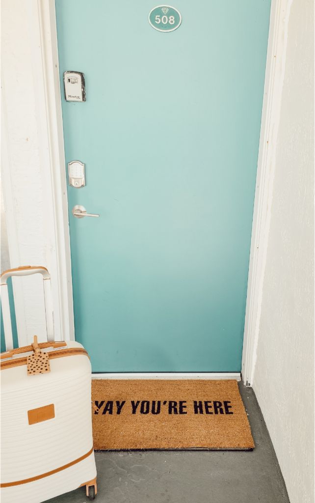 A teal door with a doormat that reads "WAY YOU'RE HERE" and a number "508" above it.