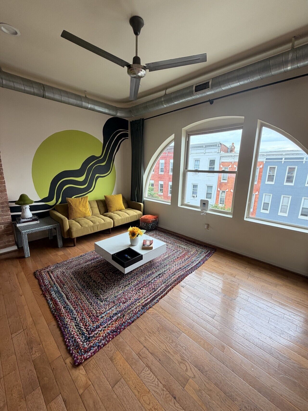 Een moderne woonkamer met een bank, salontafel en een groot raam met uitzicht op gebouwen.