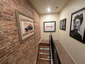 A staircase with a brick wall on one side and framed artwork on the other.